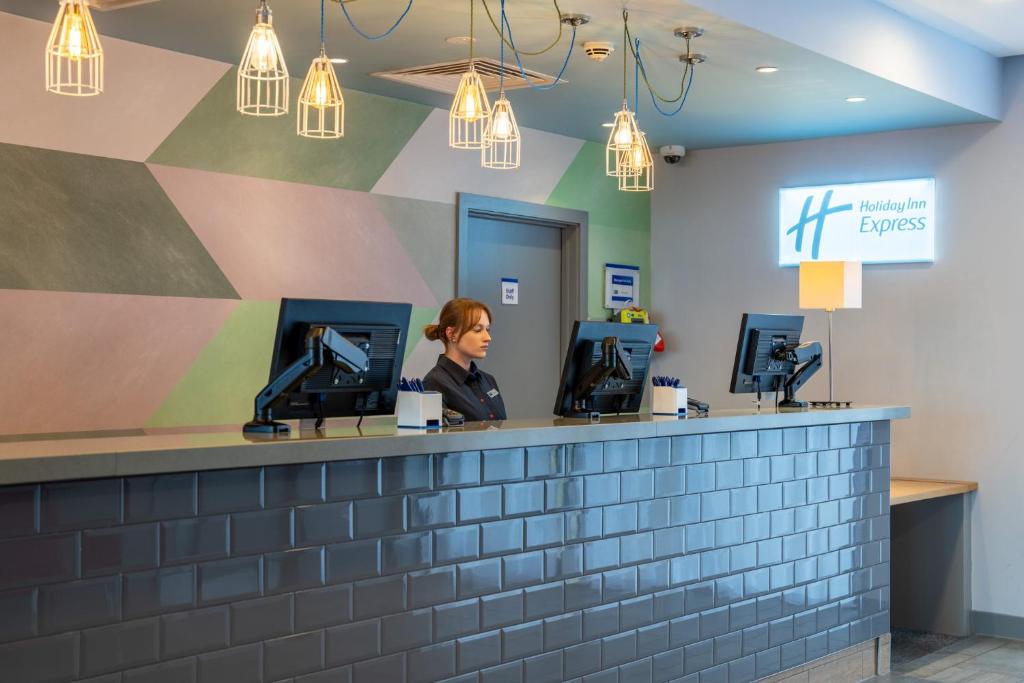 a woman sitting at a counter in a waiting room at Holiday Inn Express Aberdeen Airport by IHG in Dyce