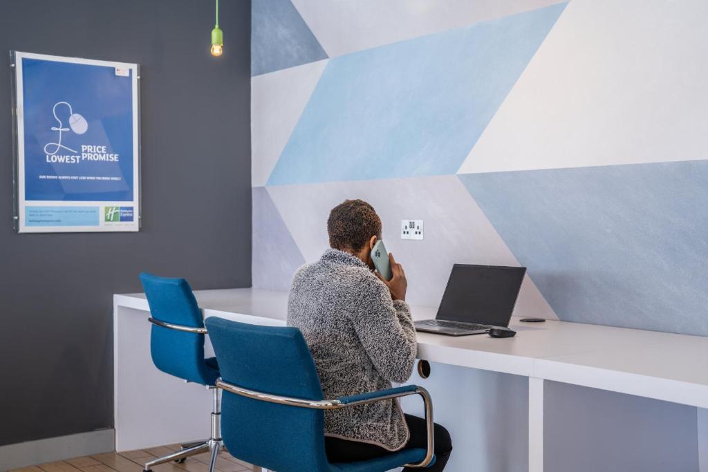 a man sitting at a desk talking on a cell phone at Holiday Inn Express Aberdeen Airport by IHG in Dyce