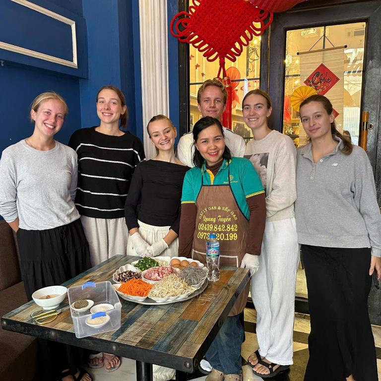 Un grupo de personas de pie alrededor de una mesa con comida. en Little Charm Hanoi Hostel, en Hanói