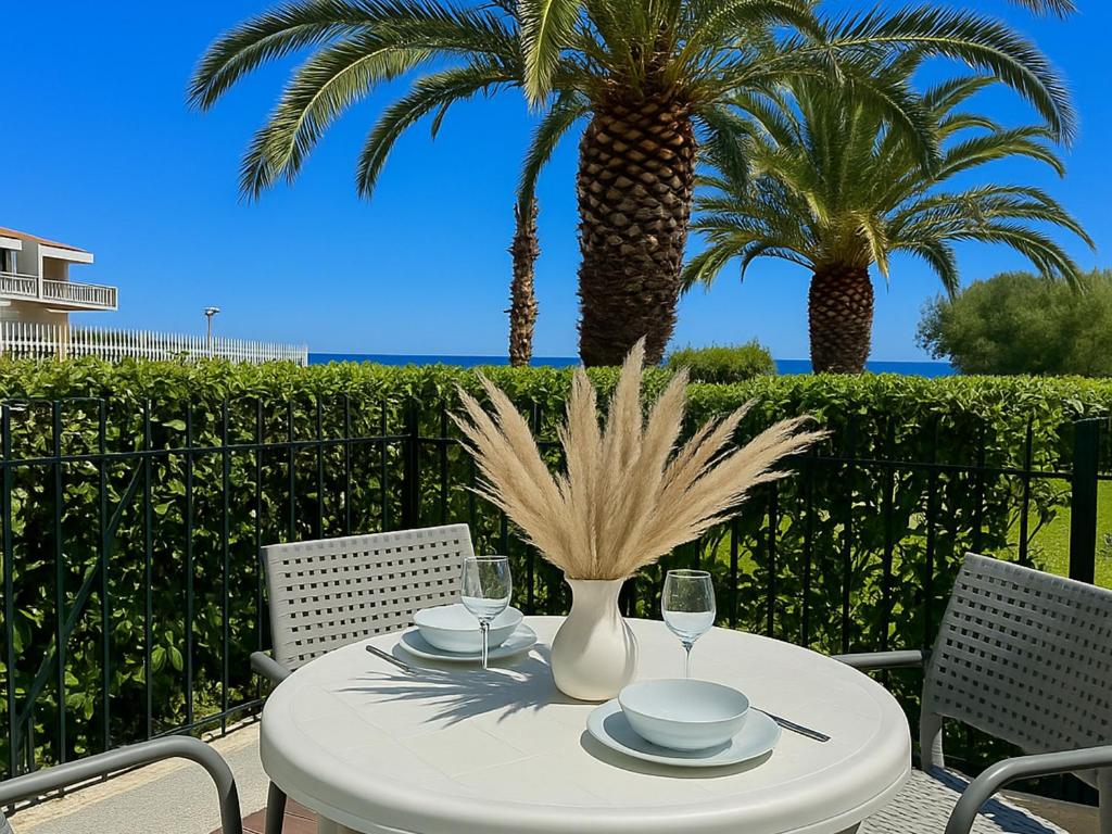 une table blanche avec deux chaises et des palmiers dans l'établissement Studio moderne avec piscine, proche plage et commodités, Saint-Cyprien - FR-1-732-71, à Saint-Cyprien