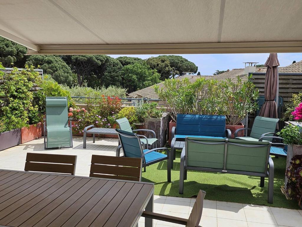 un groupe de chaises et de tables sur une terrasse dans l'établissement Appartement 3 chambres proche mer, terrasse sud - FR-1-768-120, à La Garonnette-Plage