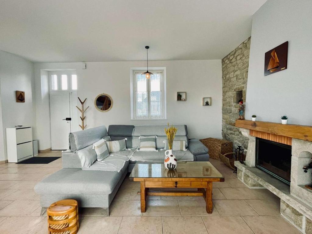 un salon avec un canapé et une cheminée dans l'établissement Maison 3 étoiles rénovée 2025, terrasse, accueil animaux, bord de mer - FR-1-542-71, à Pleumeur-Bodou