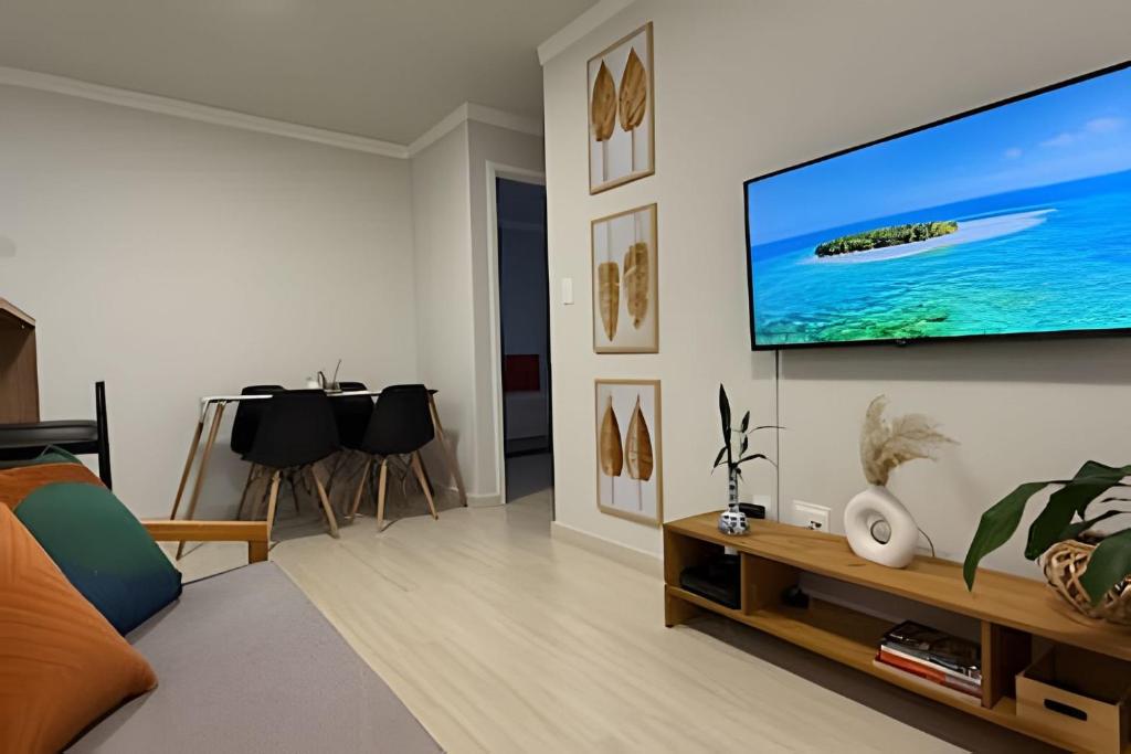 un salon avec une télévision à écran plat sur un mur dans l'établissement Apto Lindo com Jardim Privativo - Oficinas, à Ponta Grossa