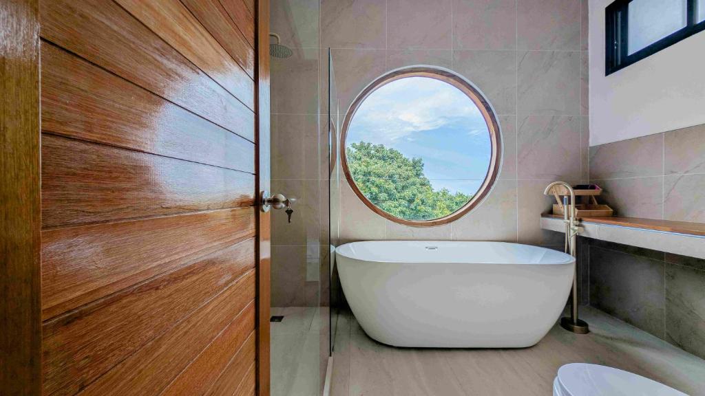 a bathroom with a white tub and a round window at v32A Blue Horizon Haad Yao, Seaview 3BR Apartment 1st Floor in Ko Phangan