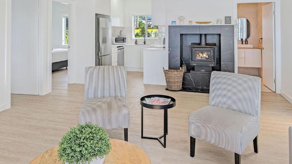 a living room with two chairs and a fireplace at Billyz Basin by Experience Jervis Bay in St Georges Basin