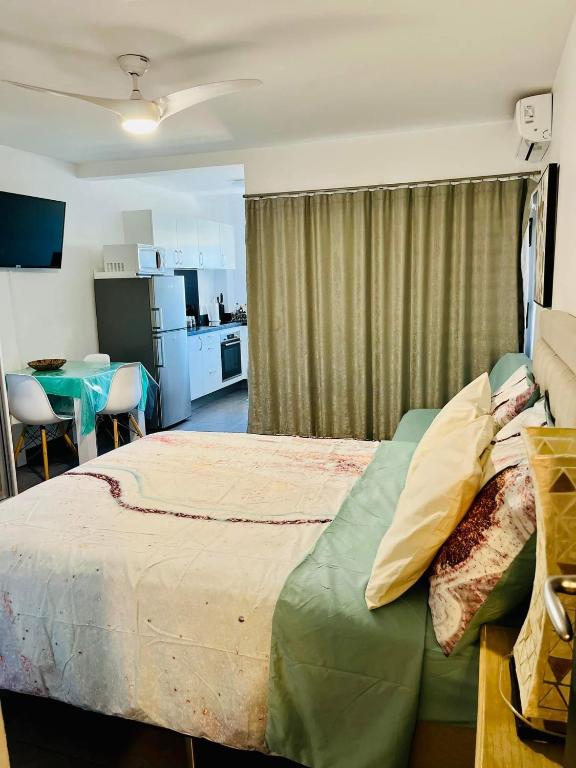 a bedroom with a large bed and a kitchen at Tehautahi Cozy Lodge 1 in Papeete