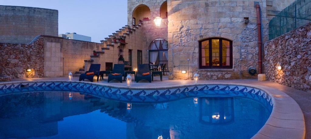 a house with a swimming pool in front of a building at Villa Joy Farmhouse in Xagħra