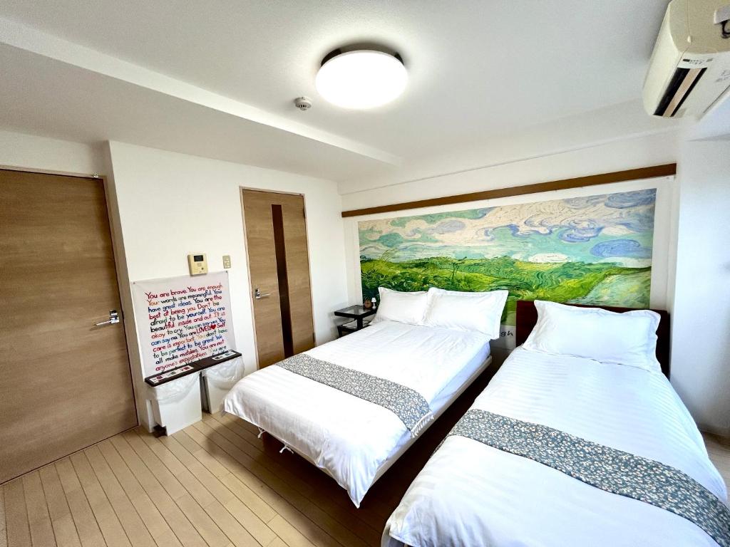 two beds in a room with a painting on the wall at 关西机场直达 i Home Osaka URBAN NOOK 舒适双床房 天下茶屋站步行3分钟 in Osaka