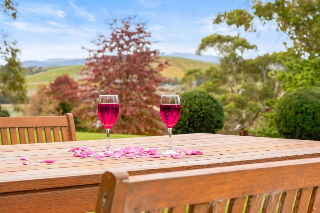 two glasses of red wine sitting on a wooden table at Yarra Valley 2BR Lux Vineyard Retreat in Dixons Creek