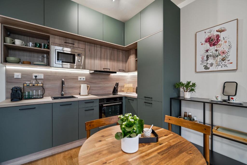 a kitchen with green cabinets and a wooden table at Apartmán Klement in Znojmo