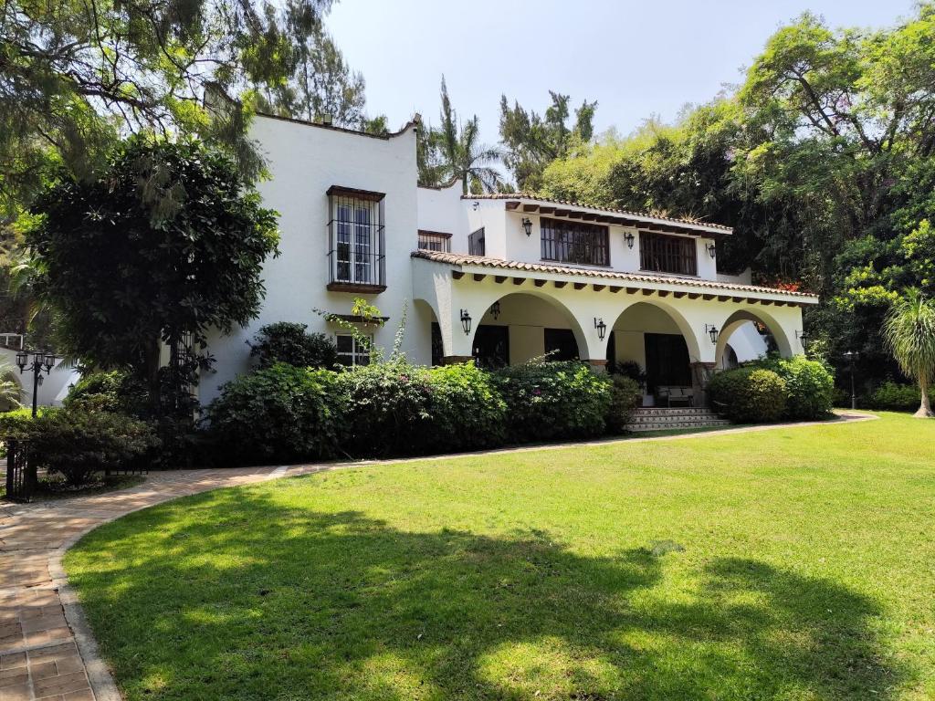 a white house with a lawn in front of it at Casa de las Conchas Cuernavaca in Cuernavaca