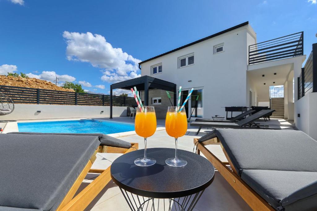 two glasses of orange juice sitting on a table on a patio at Ferienhaus Kala Maslenica in Maslenica