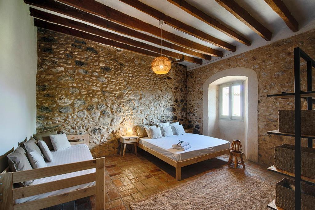 a room with a stone wall with a couch and a table at Mas Piarnau in Vilasacra