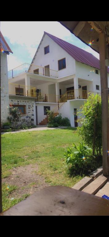 Un gran edificio blanco con un patio delante. en Bujtina Kometa, en Theth