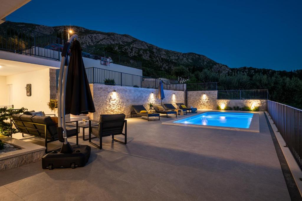 a patio with a pool and chairs and an umbrella at Villa Casa de Flores in Dubravka