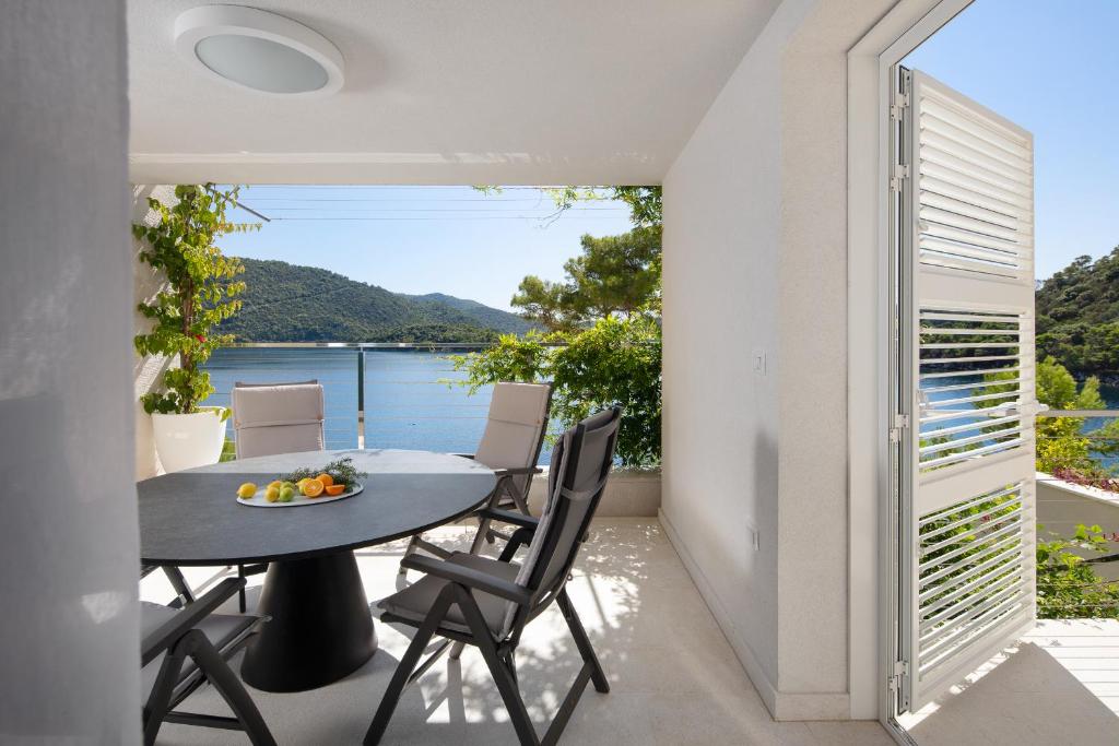 a balcony with a table and chairs and a view of the water at Duka & Piko apartmani 1 in Lastovo