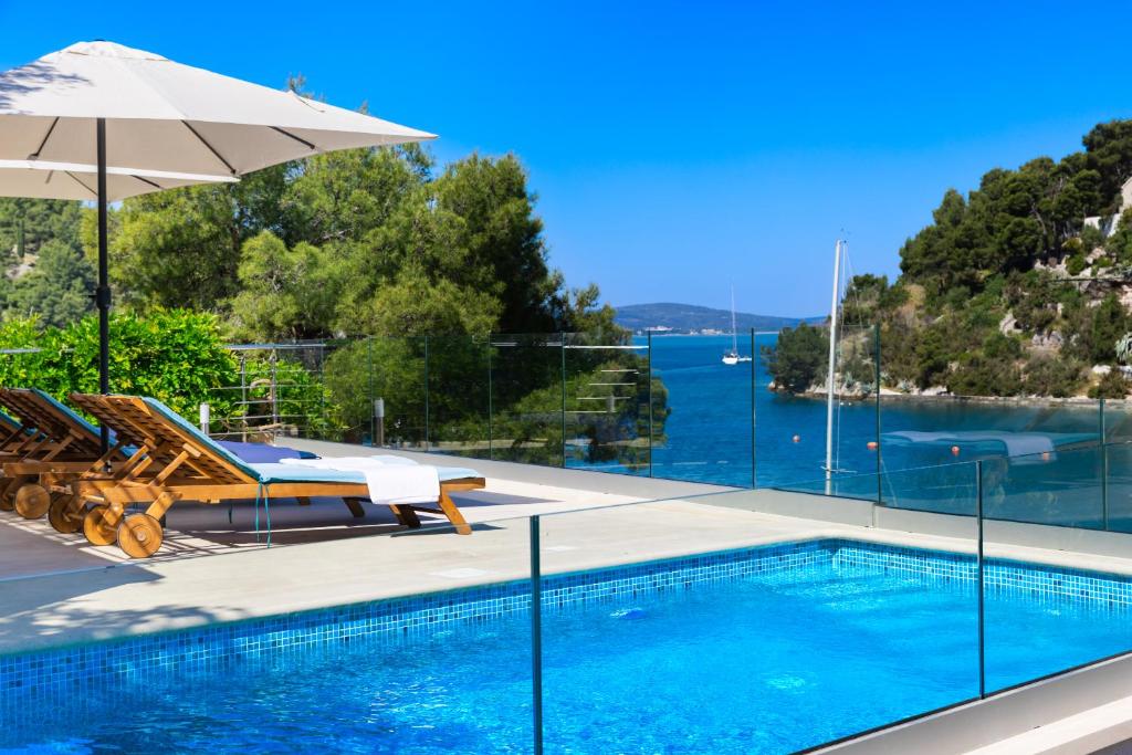 a swimming pool with a view of the water at VILLA PHILIPPA - luxurious five-room villa - idyllic location - first row to the sea - spectacular view of the sea bay - unforgettable sunsets - 15 minutes from Supetar ferry port - free parking - private heated pool in Sutivan