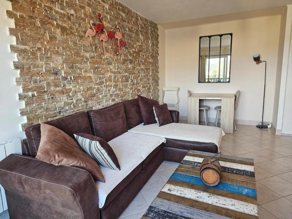 un salon avec un canapé et un mur de briques dans l'établissement Spot idéal à 800m de la plage, à Blonville-sur-Mer