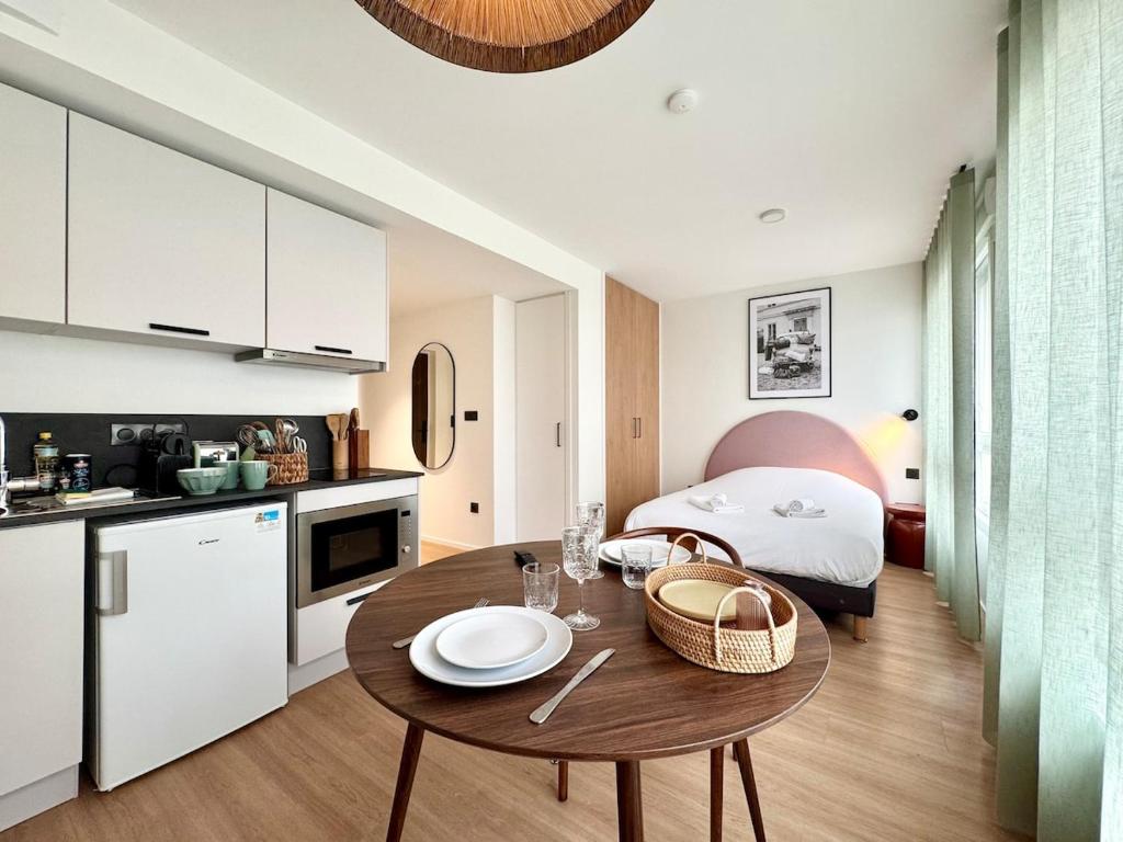 une cuisine et un salon avec une table et un lit dans l'établissement We Live Inn Sharies Reims B303, à Reims