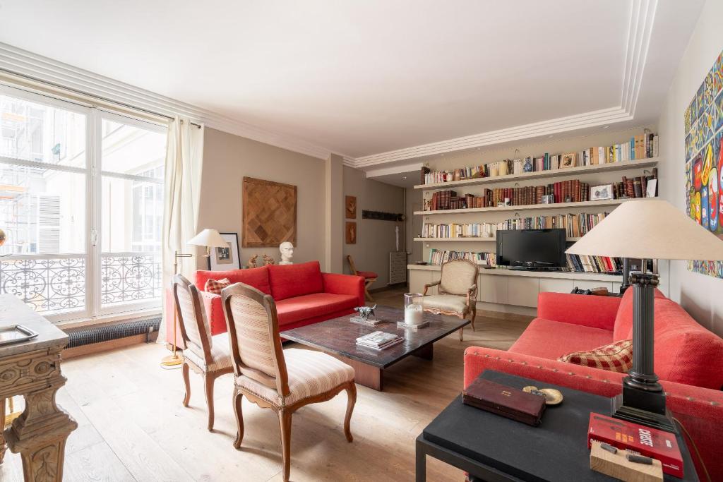 Elle comprend un salon doté d'un mobilier rouge et d'une grande fenêtre. dans l'établissement Veeve - Artful Escape, à Paris