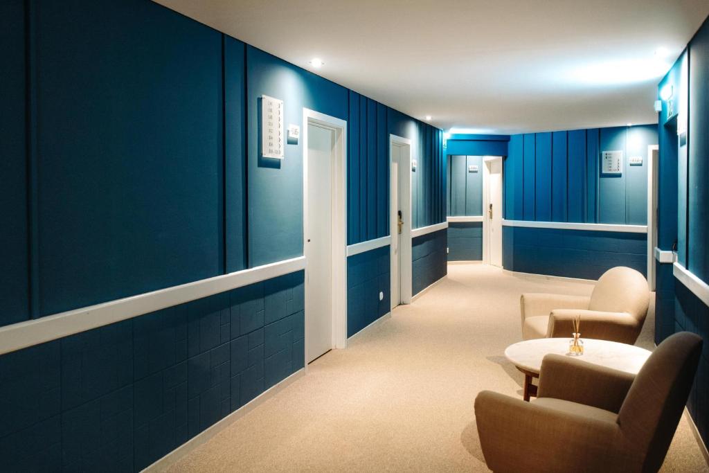 a hallway with blue walls and chairs and a table at Velamar Boutique Hotel - Adults Friendly in Albufeira