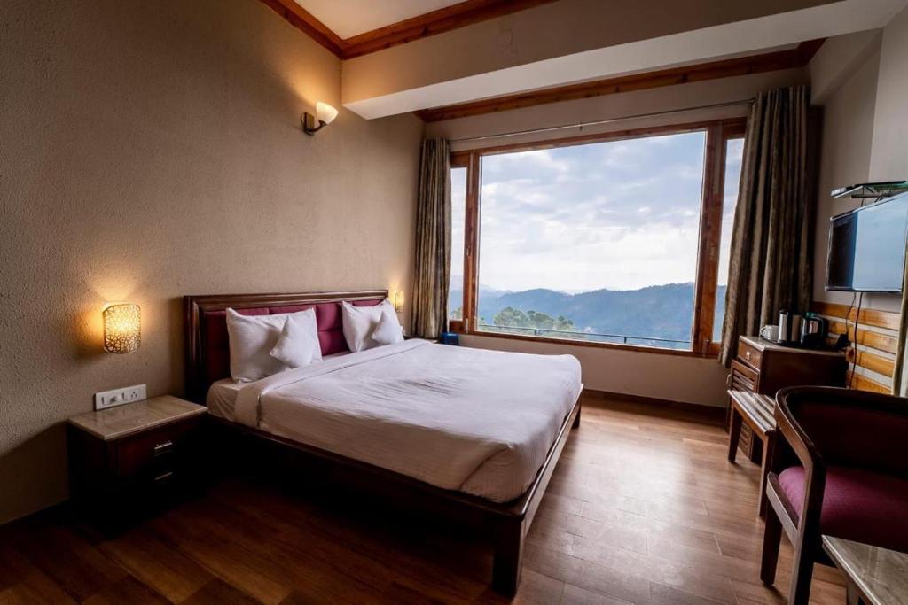 卡绍利Pine Vista Resort !! A Complete Resort with all Facilities # A Beautiful Mountain View # Best Selling Property的一间带床和大窗户的卧室