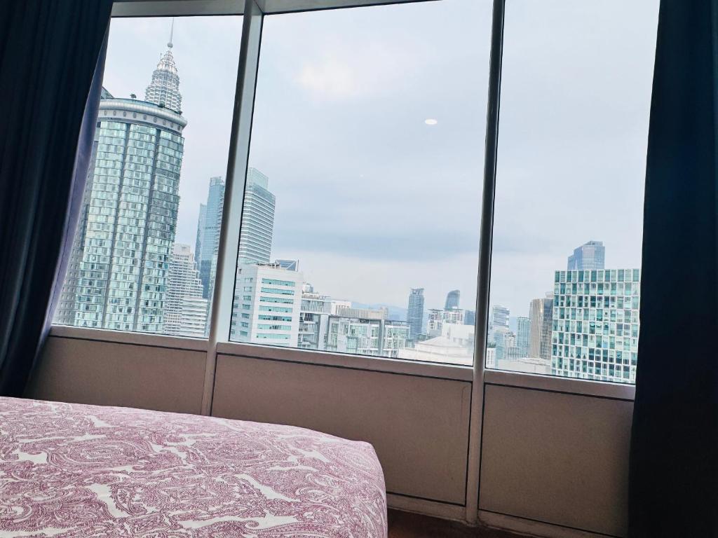 a bedroom with a view of the city from a window at Vortex Suites Klcc 2bedroom & 3bedroom apartment in Kuala Lumpur