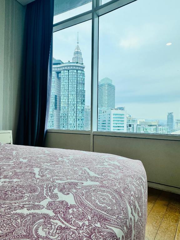a bedroom with a view of a city from a window at Vortex Suites Klcc 2bedroom & 3bedroom apartment in Kuala Lumpur