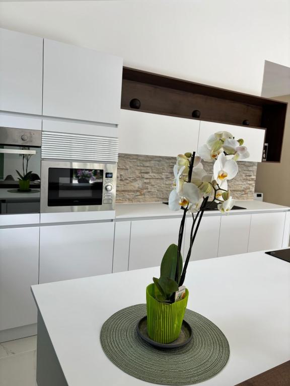 une cuisine blanche avec un vase de fleurs sur une table dans l'établissement La Champoternoise, à Belval-sous-Châtillon