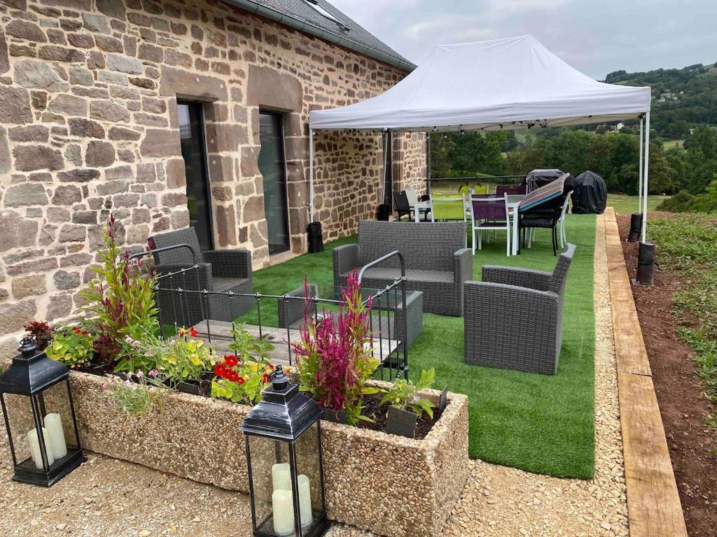 d'une terrasse avec une table et des chaises sous un parasol blanc. dans l'établissement Renovated house with hot tub, gîte de la vicairie Nouvelle-Aquitaine, à Lagleygeolle