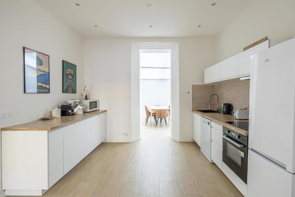 une cuisine avec des armoires blanches et un plancher en bois dans l'établissement LE WINDSOR avec extérieur, spacieux et chaleureux pour un plaisir partagé, à Cannes