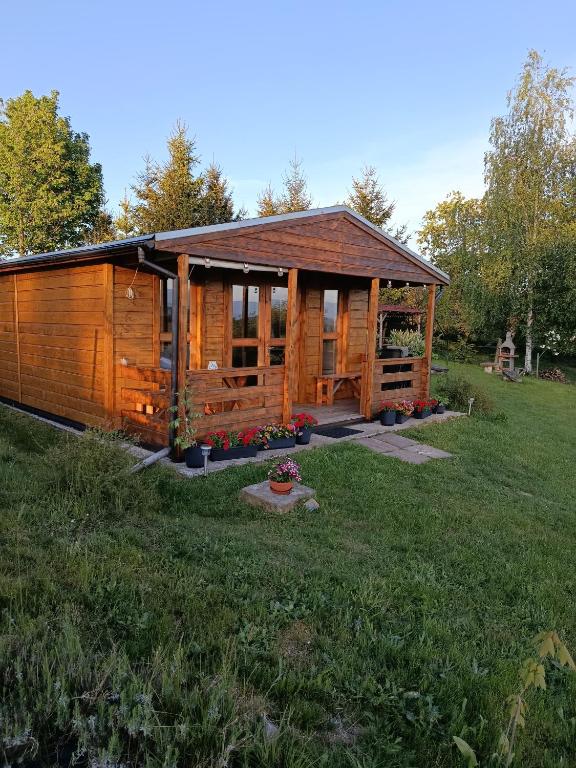 a large wooden cabin in a grassy field at Domek letniskowy Radomice in Wleń