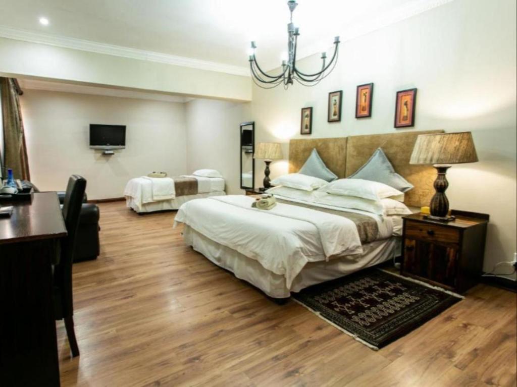 a large bedroom with two beds and a chandelier at Royl Court Guesthouse in Kimberley