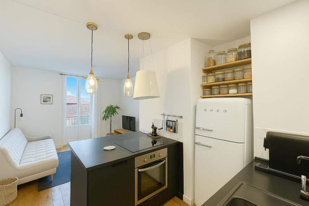 une cuisine avec un réfrigérateur blanc et une table dans l'établissement Élégant cocon avec balcon à deux pas des vagues, à Biarritz