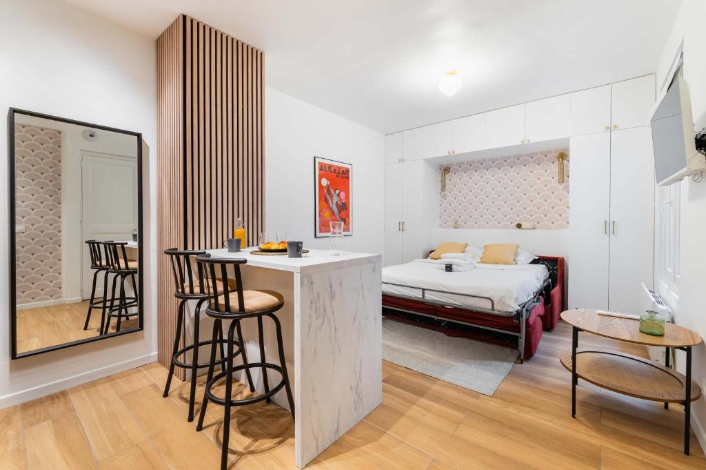Cet appartement comprend une chambre avec un lit et une cuisine avec un bar. dans l'établissement Studio parisien coeur montmartre - Paris 18 - 2p, à Paris