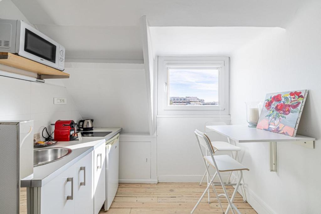 une cuisine blanche avec un évier et une table dans l'établissement LE VANILLE studio cosy au cœur de la Banane, à Cannes