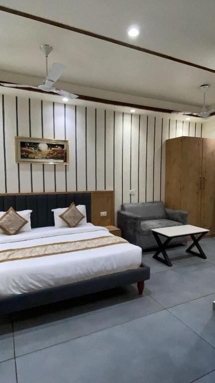 a bedroom with a bed and a bench and a table at Rosewood Grand in Faridabad