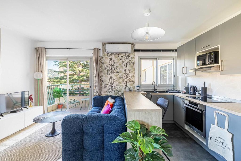 un salon avec un canapé bleu et une cuisine dans l'établissement LA PALMERAIE joyeux studio avec balcon, à deux pas de la Banane, à Cannes