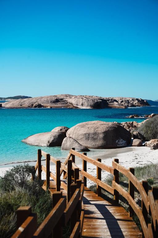 un sentiero in legno verso la spiaggia con rocce e acqua di Folktales Rest - Tiny House Unique Stay a Esperance