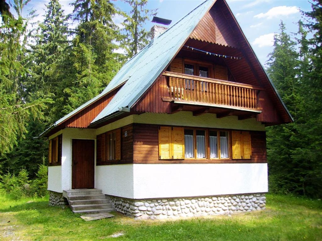 a house with a gambrel roof and a porch at Chata v lese pri rieke Bela in Pribylina