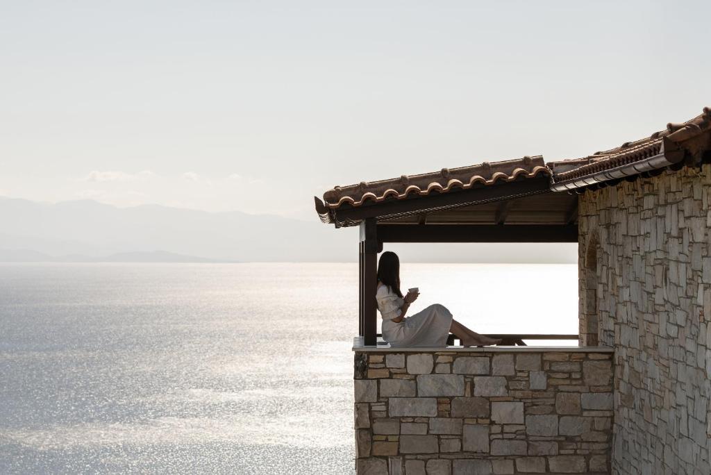 a woman sitting on the ledge of a building at Karavia Lux Inn in Afissos