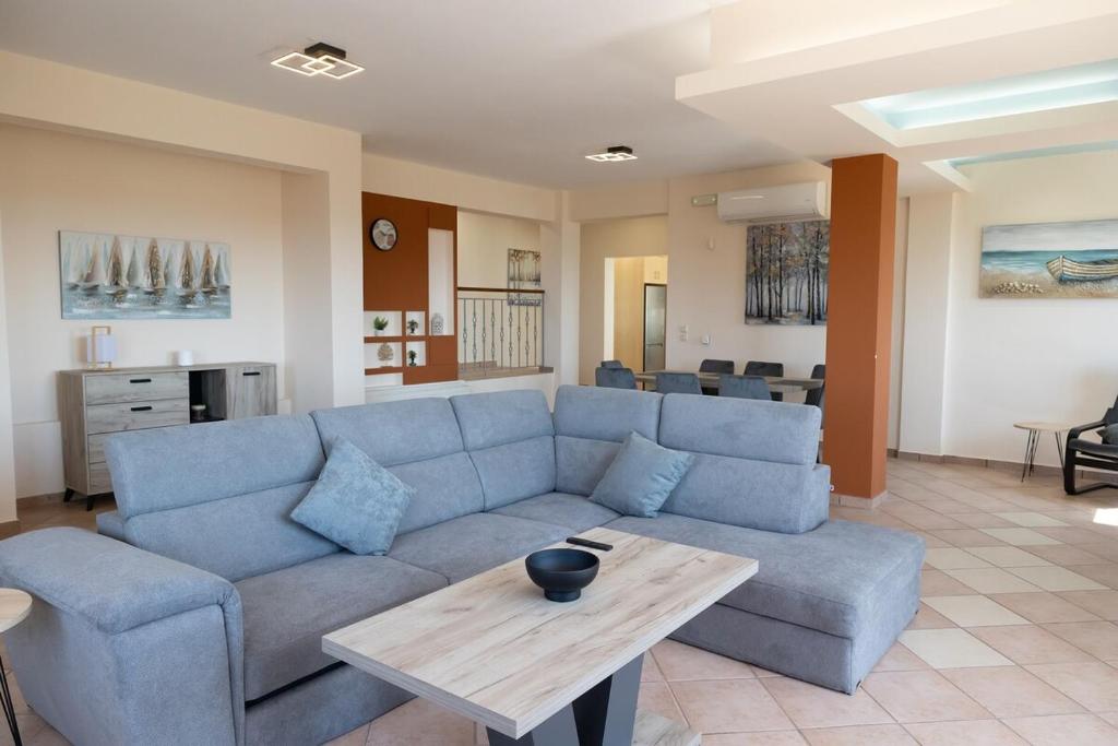 a living room with a blue couch and a table at Aethra Villa in Sounio