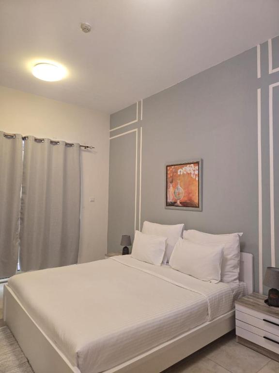 a bedroom with a large white bed with white pillows at Al Raya Hotel Apartments in Dubai