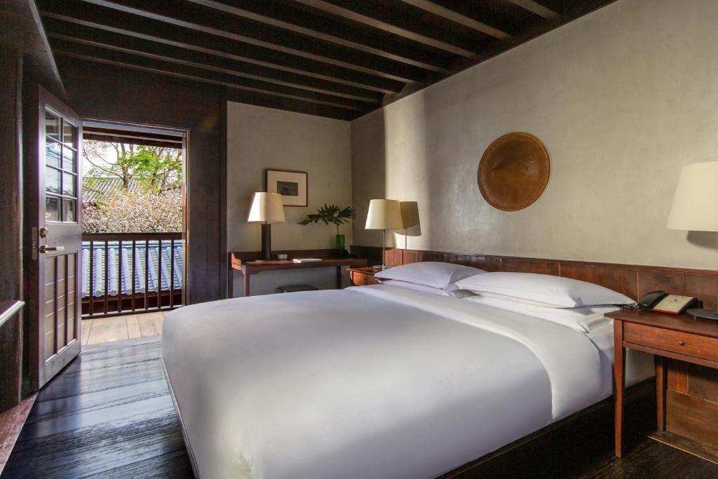 Un dormitorio con una gran cama blanca y un balcón. en Lijiang Old Town Lanshe hotel, en Lijiang