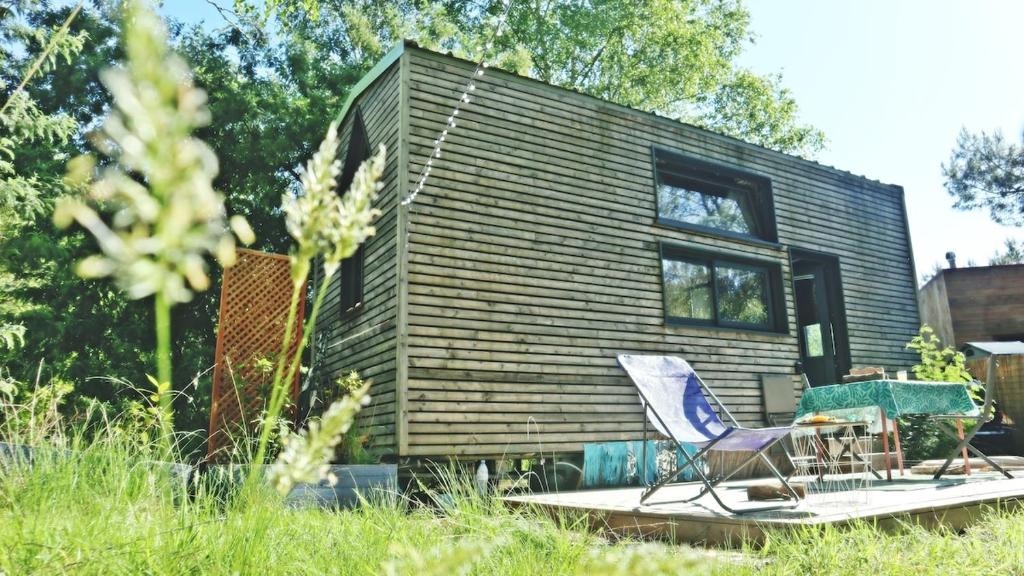 une petite maison avec une terrasse et deux chaises dans l'établissement Tiny House Boho Océan, à Naujac-sur-Mer