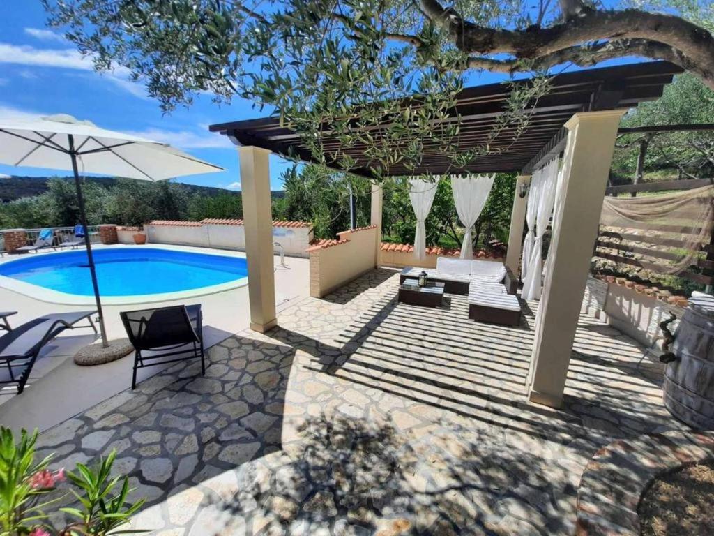 a patio with a swimming pool and an umbrella at Apartments Kampor (4235) in Kampor