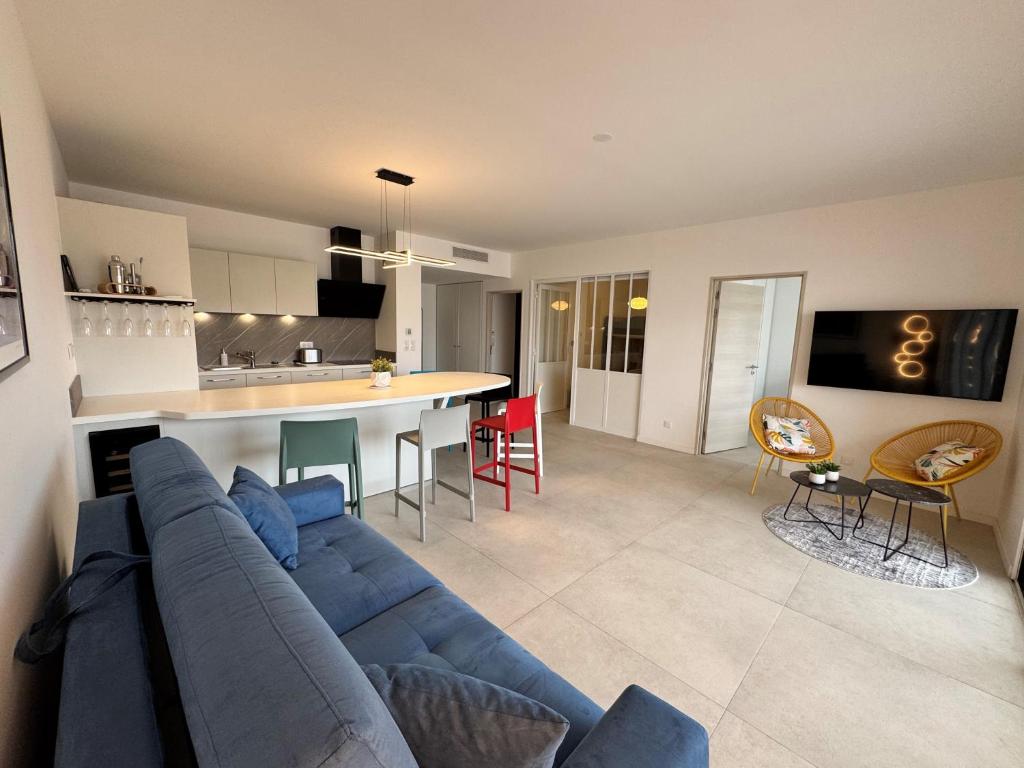 un salon avec un canapé bleu et une cuisine dans l'établissement Appartement 225, CORAL à la plage de la Conque, au Cap d'Agde