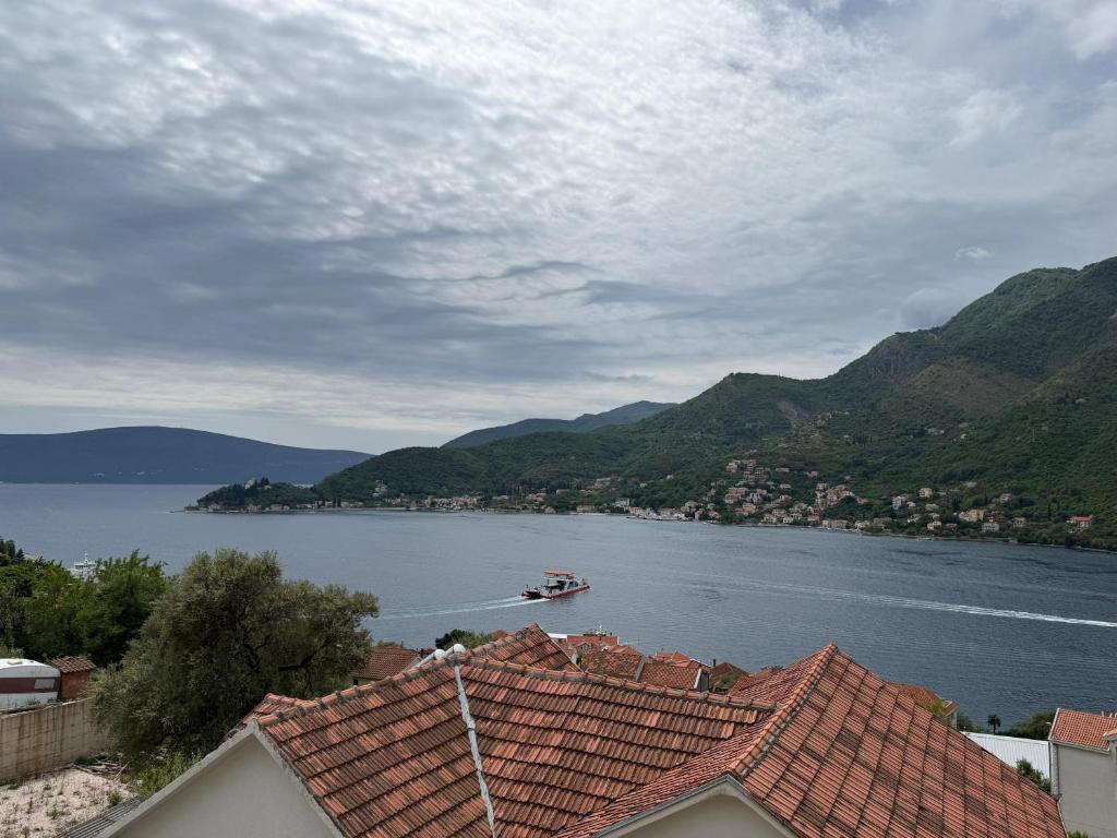 a boat on a lake with mountains in the background at Beli's Apartments in Tivat