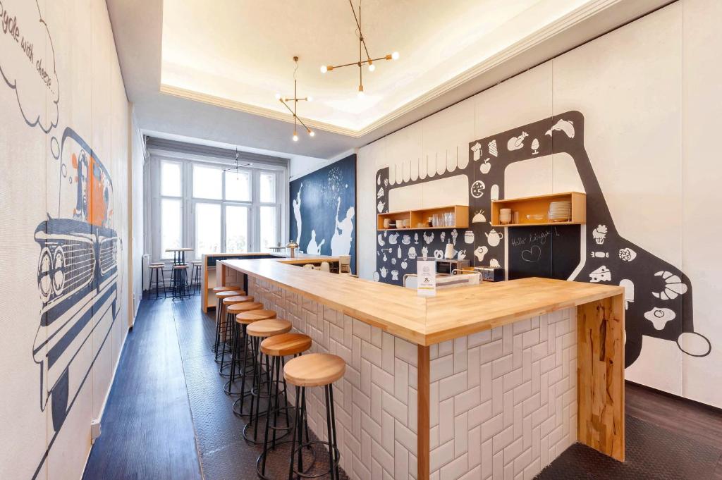 a restaurant with a bar with stools in a room at Adagio Hostel Basilica in Budapest