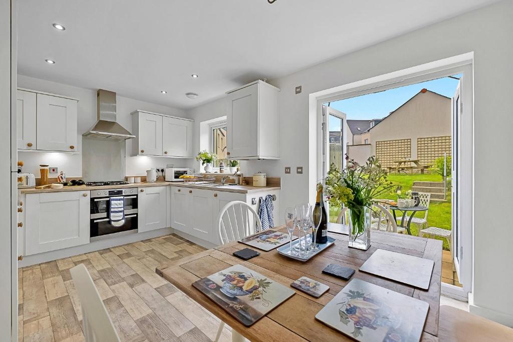 a kitchen with white cabinets and a table with flowers at Finest Retreats - Cove House in St Austell